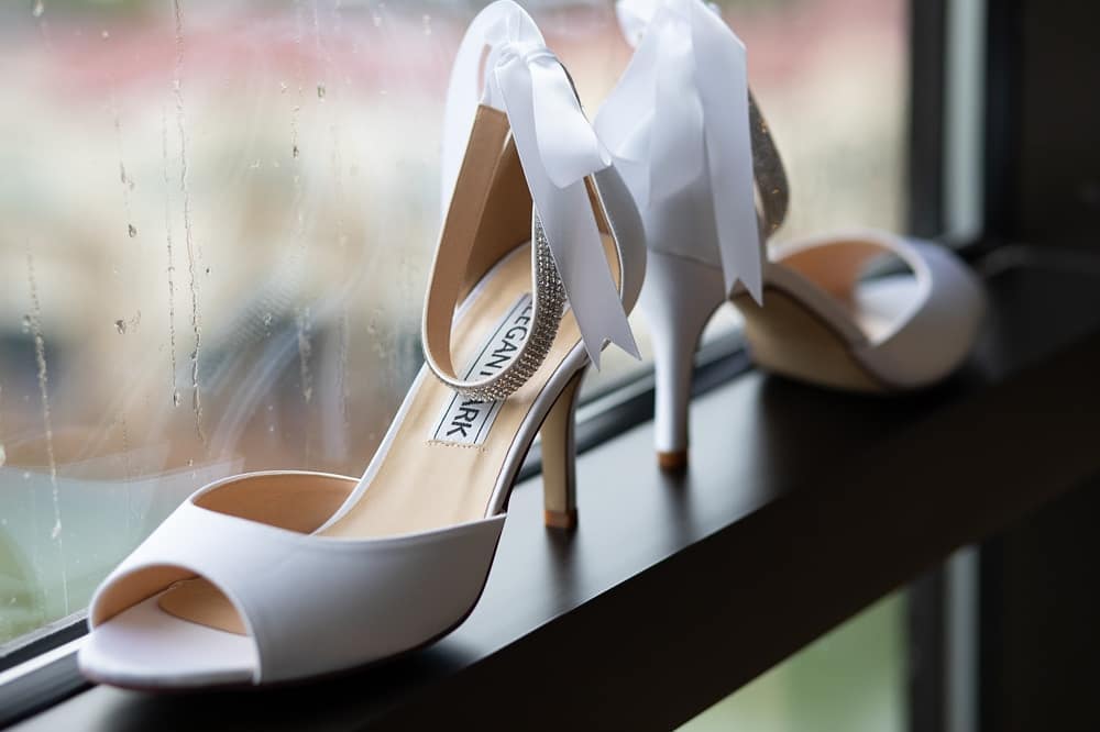 Close-up of Bride's shoes placed on a window sill while raining outside